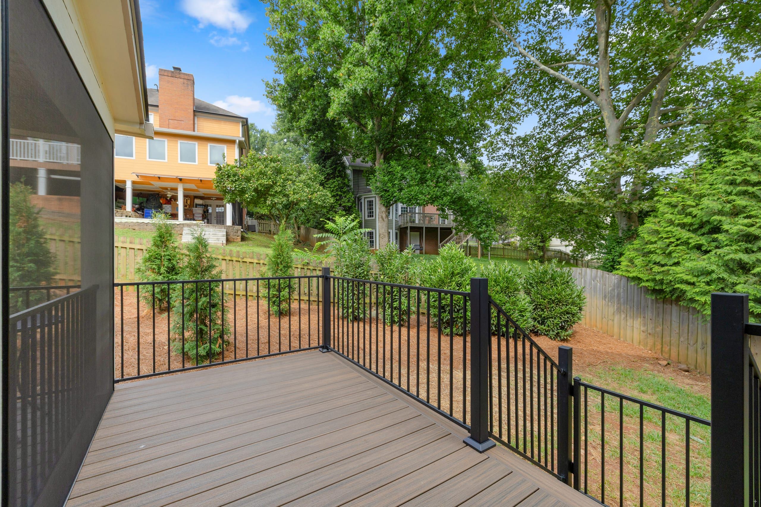 Ashgrove open deck section in Trex Enhance Naturals decking with black Fortress railing overlooking a fenced backyard