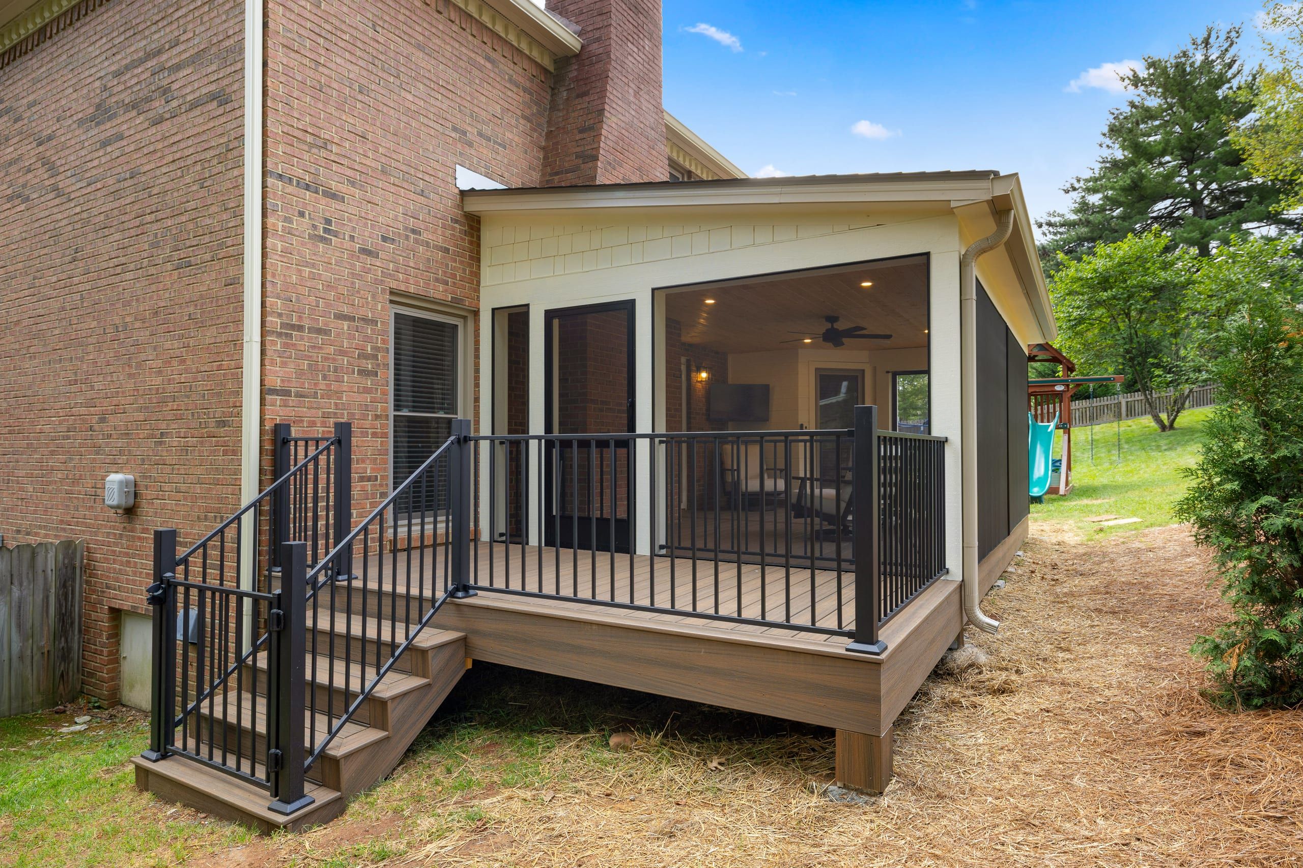 Exterior view of the Ashgrove screened porch addition with the open Trex deck and composite steps down to grade