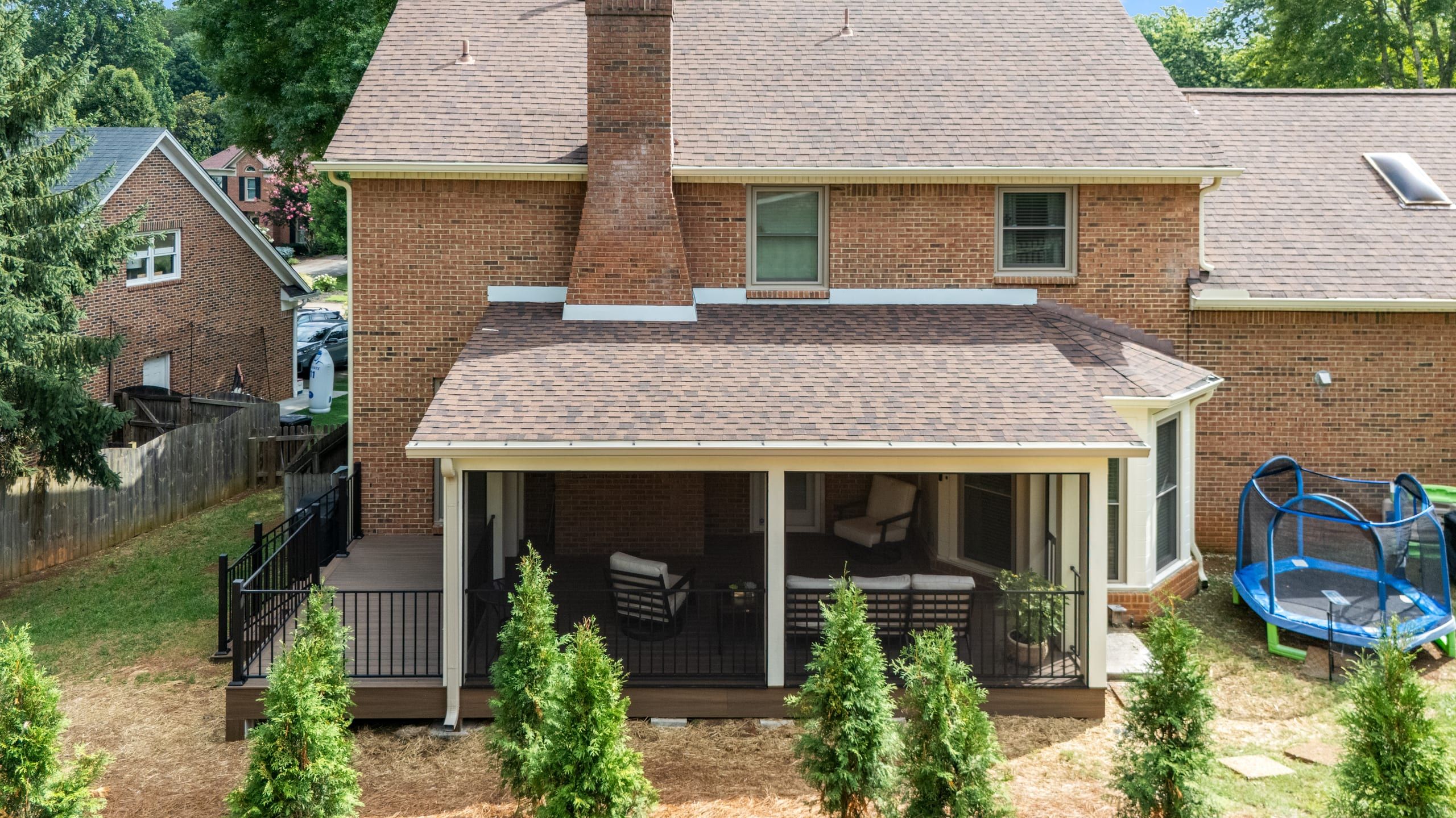 Rear elevation of the Ashgrove brick home with the screened porch addition, Trex deck, and black Fortress railing