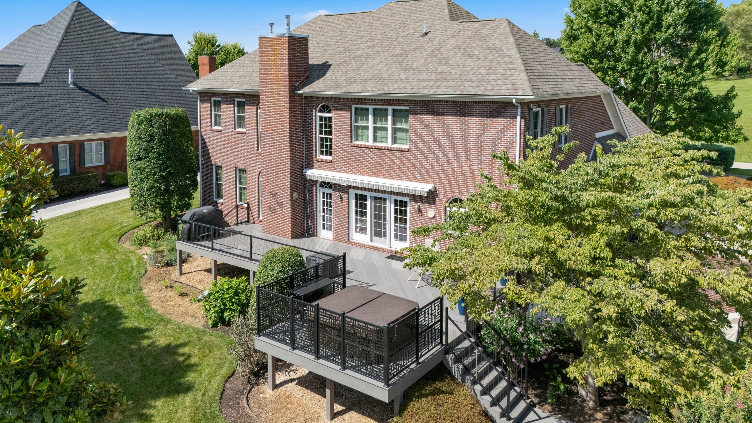 Aerial view of the Wilshire two-story brick home and its elevated wraparound composite deck